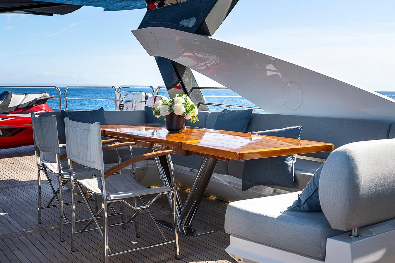 The aft deck features a stylish dining area with a polished wooden table and comfortable seating, perfect for enjoying meals with a view of the sea. aboard THIS TIME NEXT YEAR Yacht for Sale