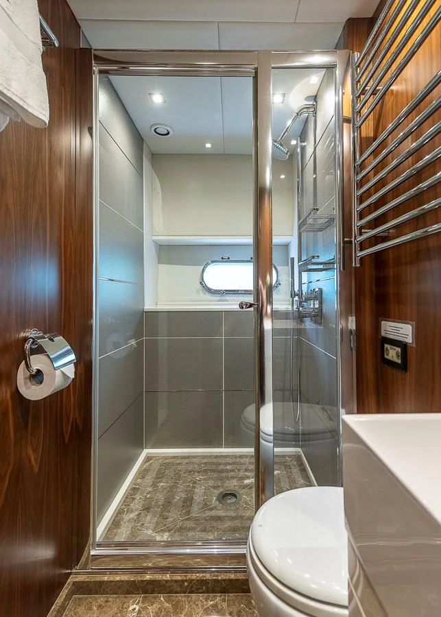 A sleek and modern bathroom with a glass-enclosed shower and elegant wood paneling. aboard THIS TIME NEXT YEAR Yacht for Sale