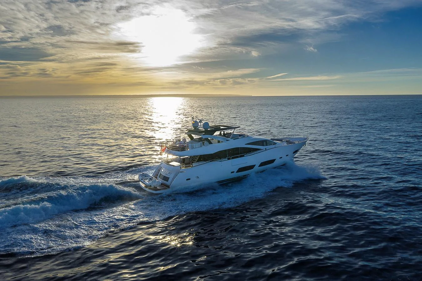 A luxurious yacht cruises through the open sea at sunset, showcasing its sleek design and elegance. aboard THIS TIME NEXT YEAR Yacht for Sale