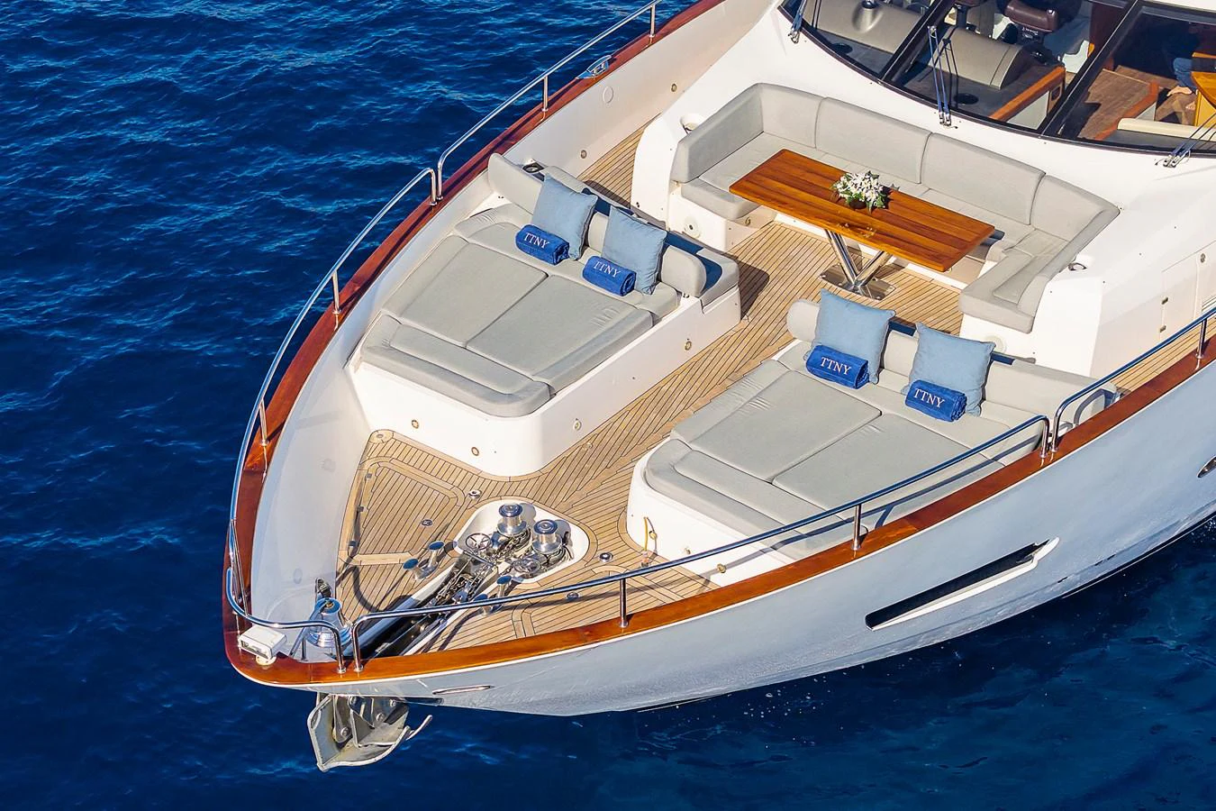 The foredeck features luxurious sun pads and a stylish seating area with a wooden table, perfect for relaxation. aboard THIS TIME NEXT YEAR Yacht for Sale