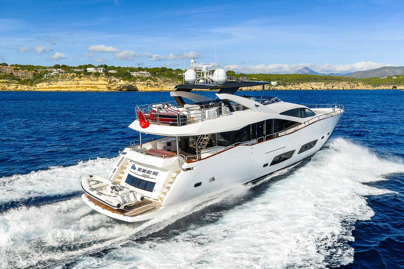 A sleek and modern yacht cruises through the open water, showcasing its elegant design and spacious deck areas. aboard THIS TIME NEXT YEAR Yacht for Sale