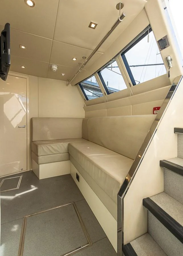 A cozy interior seating area with beige upholstery and ample natural light from the windows. aboard THIS TIME NEXT YEAR Yacht for Sale