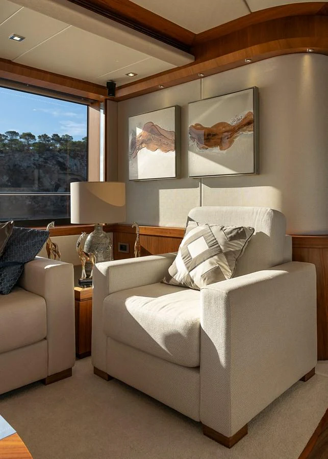 A cozy seating area with plush armchairs and tasteful decor, bathed in natural light. aboard THIS TIME NEXT YEAR Yacht for Sale