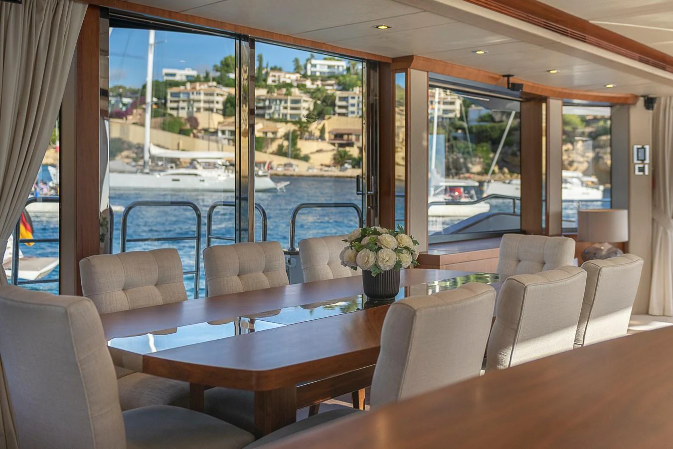 The yacht's dining area offers a luxurious setting with large windows providing stunning views of the marina. aboard THIS TIME NEXT YEAR Yacht for Sale