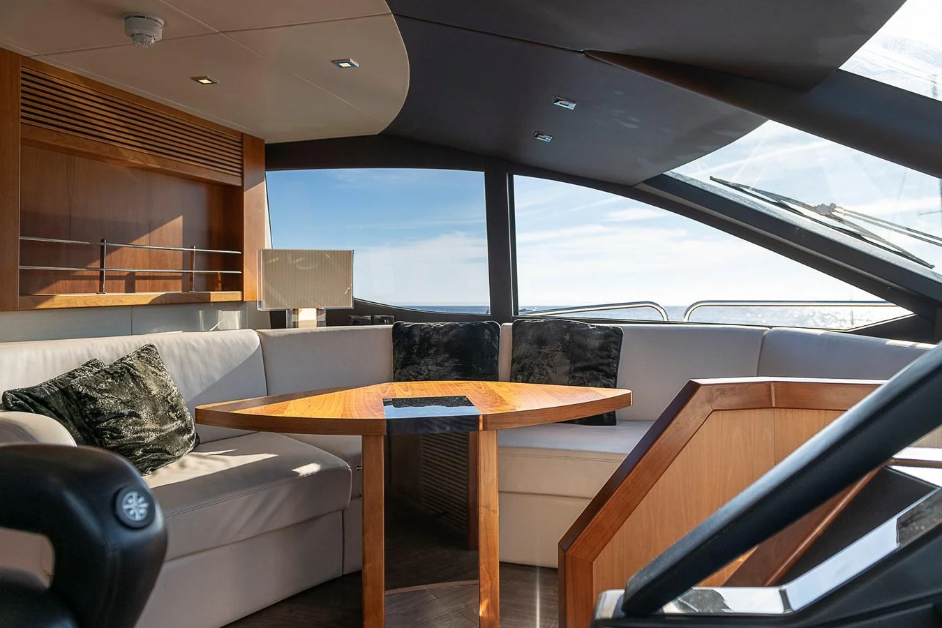 The salon features a cozy seating area with a wooden table and large windows offering panoramic views. aboard THIS TIME NEXT YEAR Yacht for Sale
