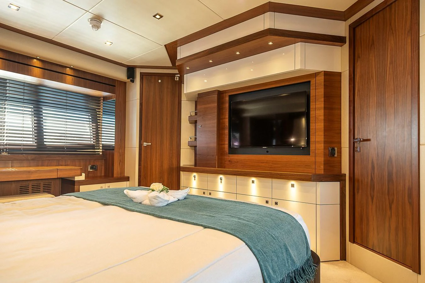 The stateroom features a luxurious bed, a flat-screen TV, and elegant wood paneling. aboard THIS TIME NEXT YEAR Yacht for Sale