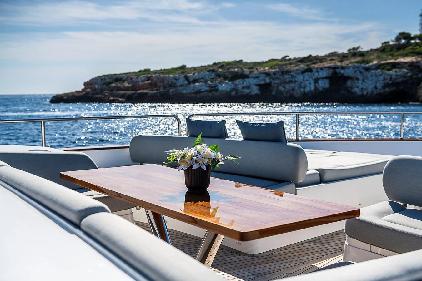 The aft deck offers a serene setting with plush seating and a polished wooden table, perfect for alfresco dining. aboard THIS TIME NEXT YEAR Yacht for Sale