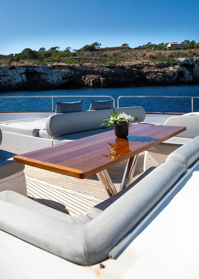 The aft deck features a stylish dining area with comfortable seating and a polished wooden table, perfect for alfresco meals with a stunning view. aboard THIS TIME NEXT YEAR Yacht for Sale
