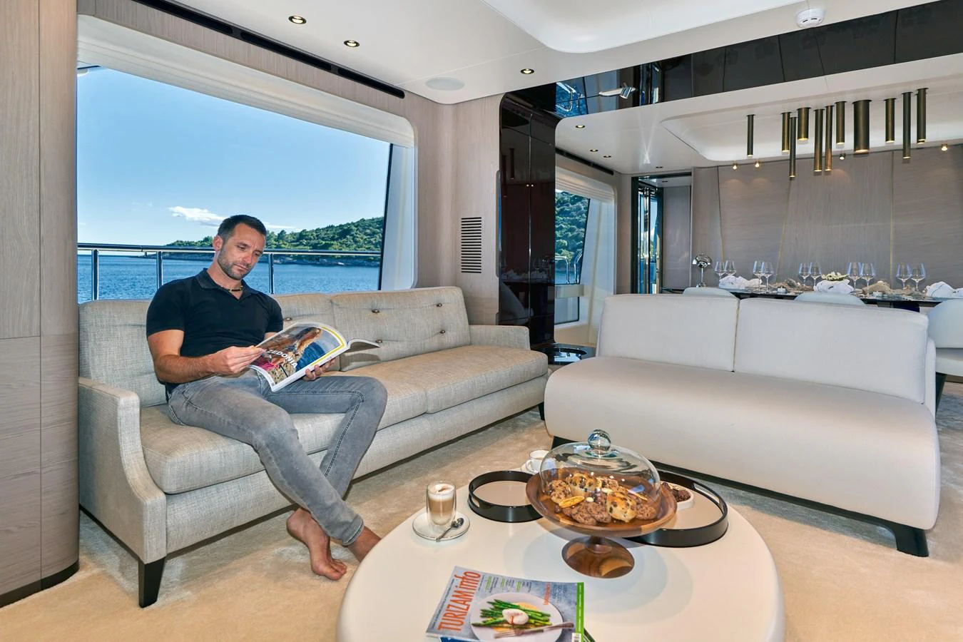 a person sitting on a couch reading a book aboard ALUMINIA TOO Yacht for Sale