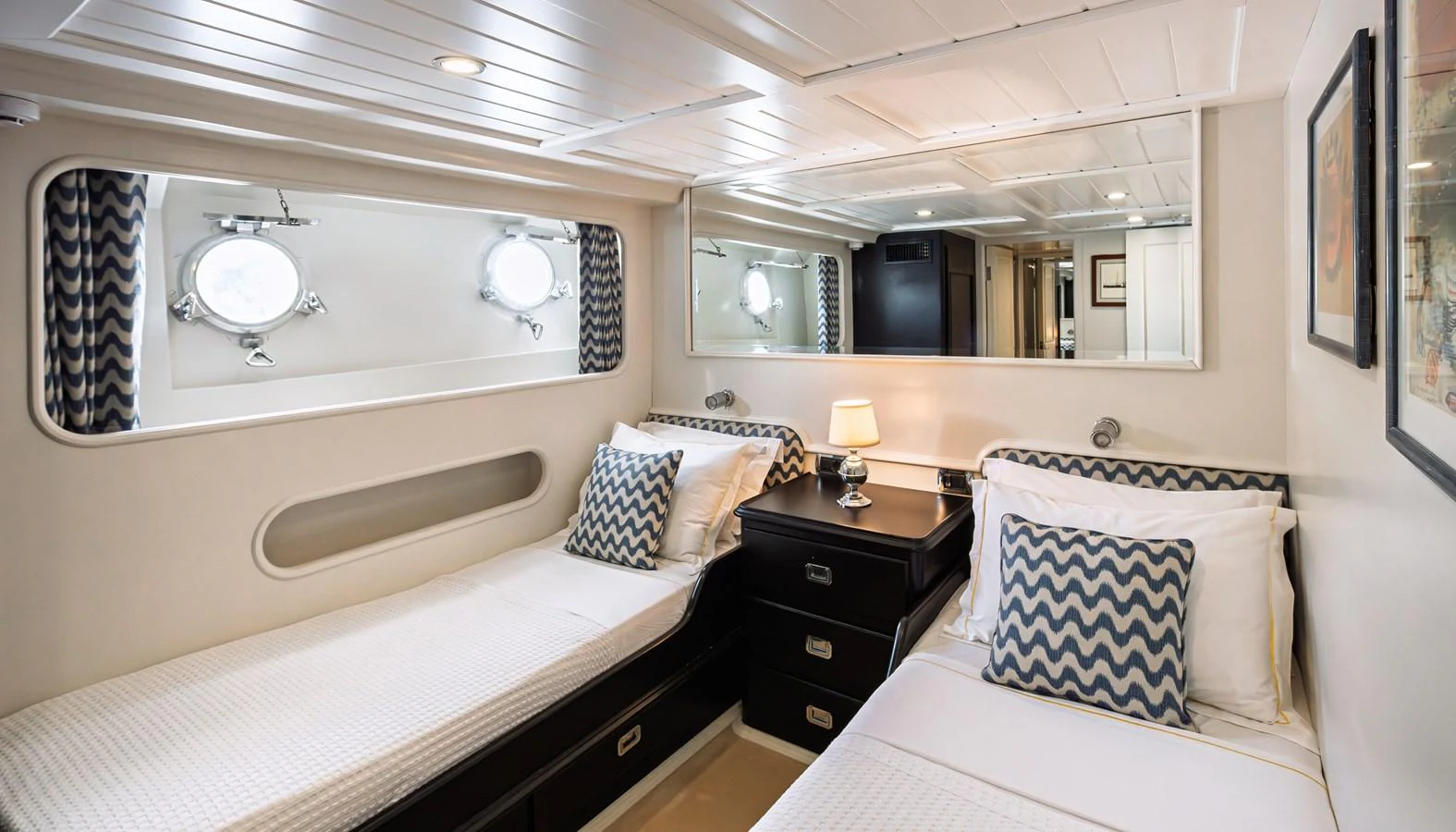 The guest stateroom features twin beds with elegant bedding and ample natural light from the portholes. aboard LADY L Yacht for Sale