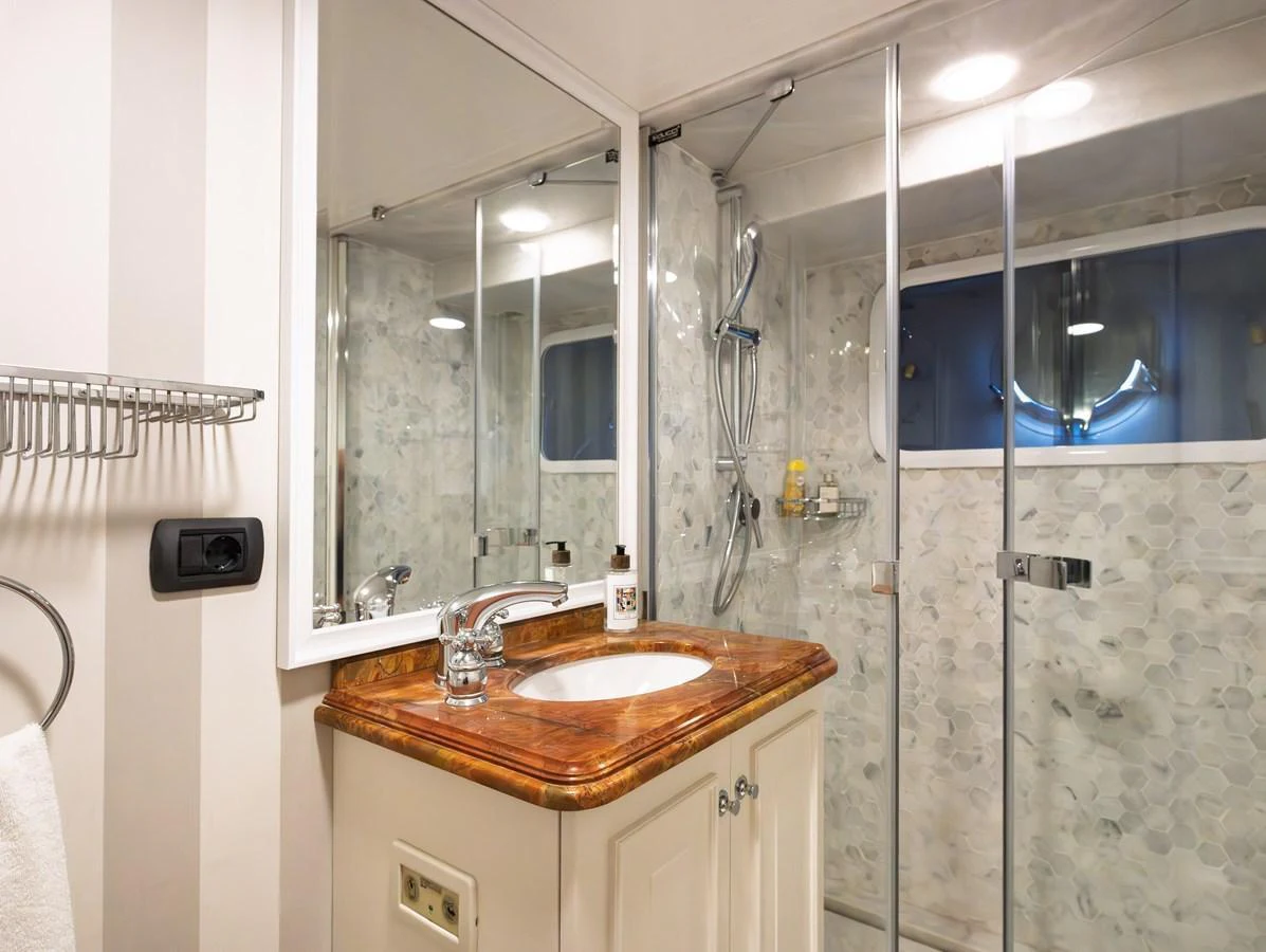 The yacht's bathroom features a sleek design with a glass-enclosed shower and a polished countertop. aboard LADY L Yacht for Sale
