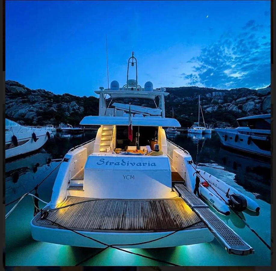 The yacht is docked at twilight, showcasing its illuminated aft deck and serene surroundings. aboard STRADIVARIA Yacht for Sale