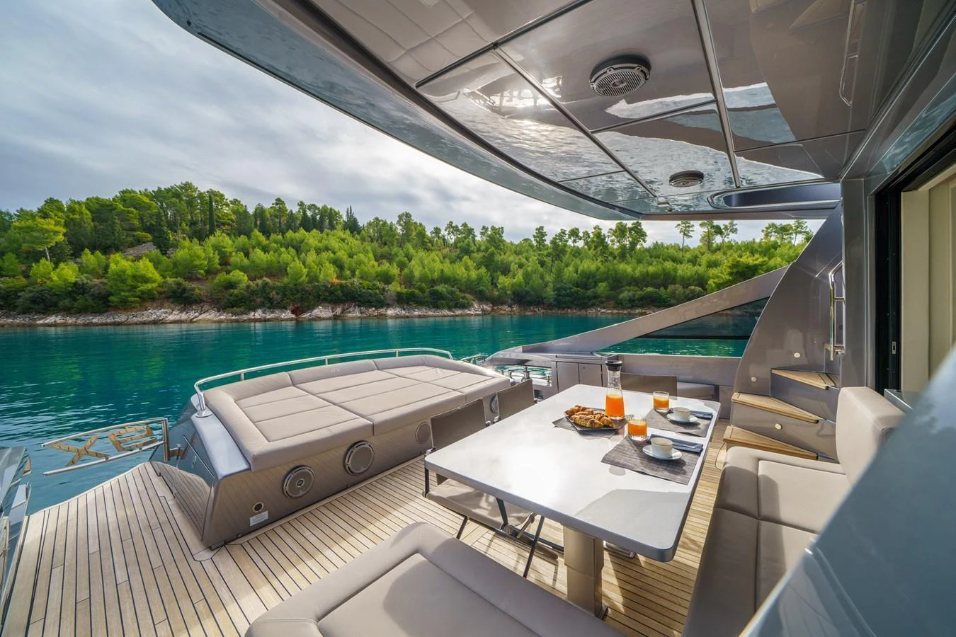 The aft deck offers a luxurious dining area with a stunning view of the surrounding waters and lush greenery. aboard MAVIS Yacht for Sale