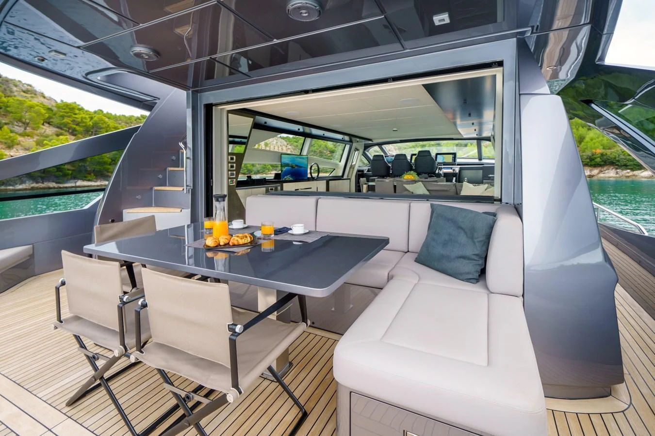 The aft deck features a comfortable seating area with a dining table, seamlessly connecting to the interior. aboard MAVIS Yacht for Sale