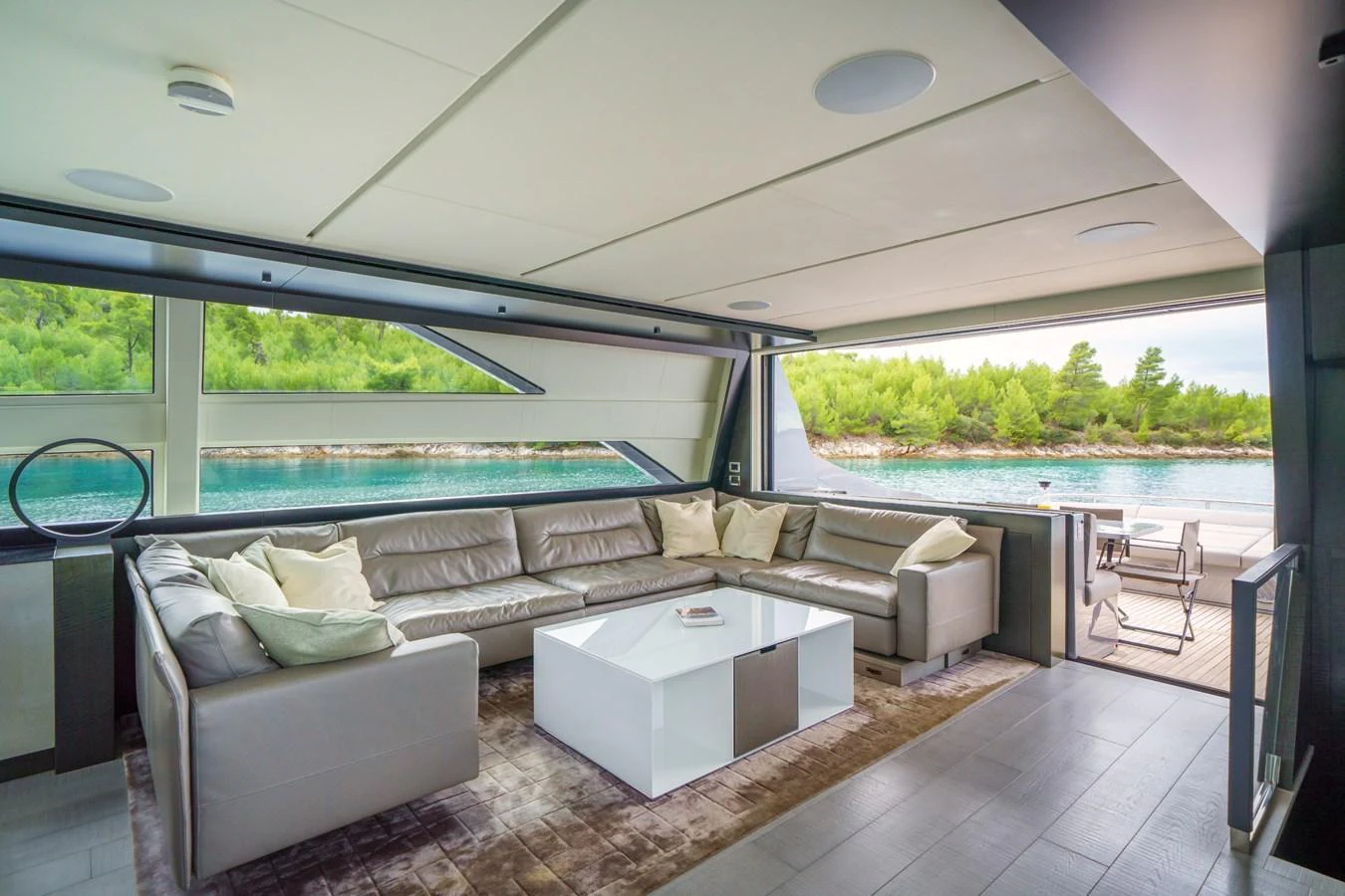The spacious salon features a large, comfortable sectional sofa with a view of the serene waters outside. aboard MAVIS Yacht for Sale