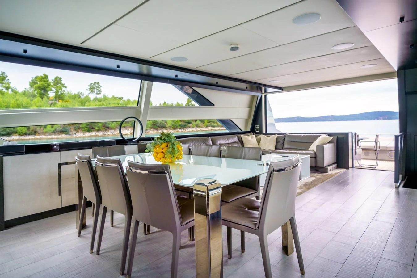 The yacht's salon features a spacious dining area with a modern table and comfortable seating, offering stunning views through large windows. aboard MAVIS Yacht for Sale