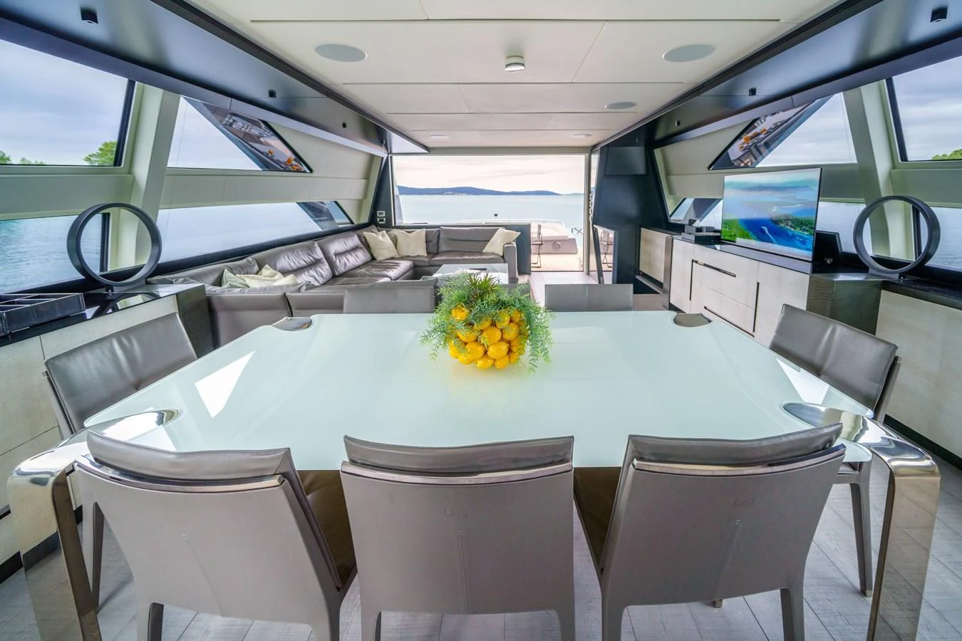 The yacht's dining area features a sleek table with seating for eight, offering a stunning view through large windows. aboard MAVIS Yacht for Sale