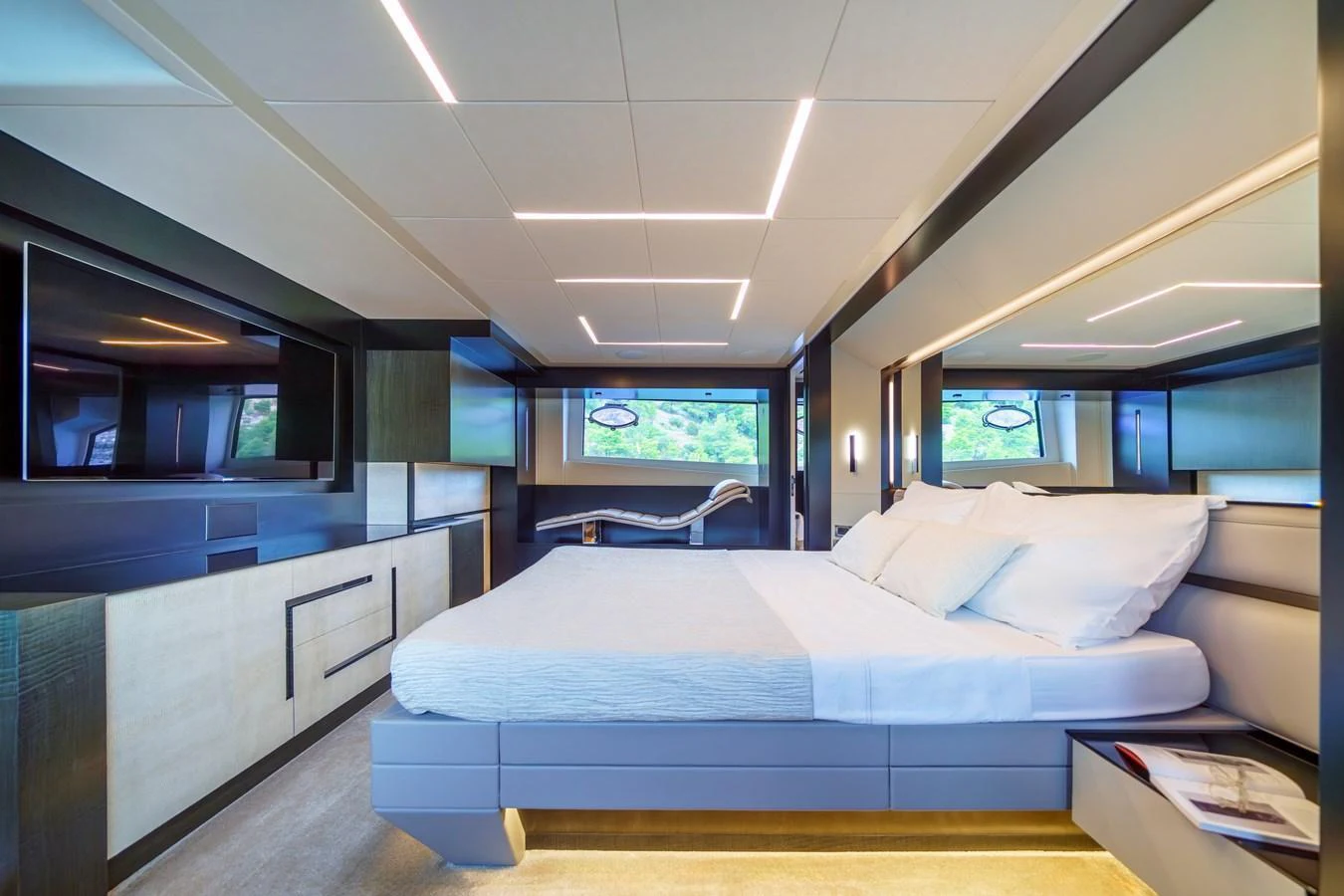 The master stateroom features a luxurious bed, modern lighting, and ample storage with a serene view through large windows. aboard MAVIS Yacht for Sale