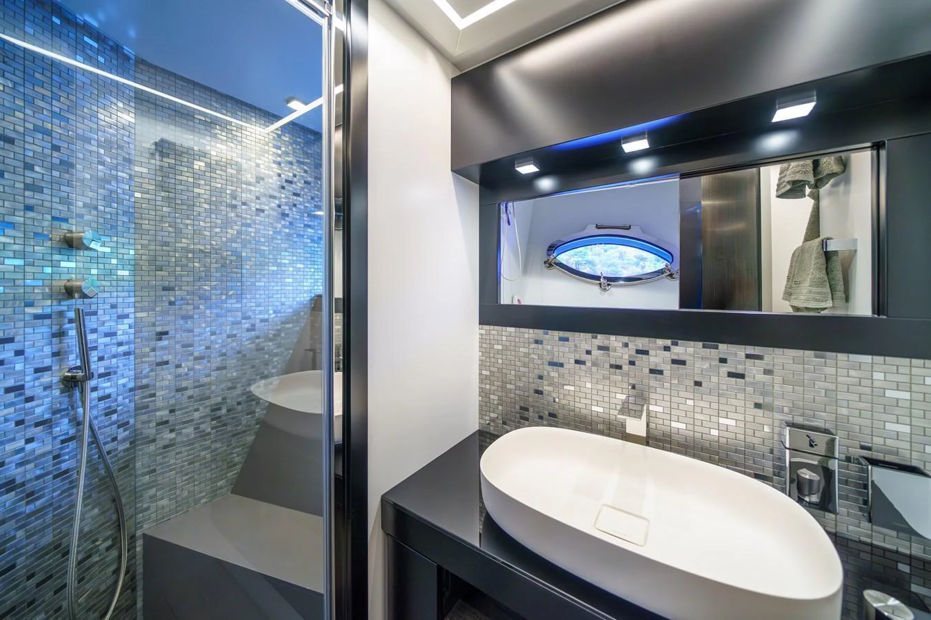 A modern yacht bathroom featuring a sleek sink, mirrored cabinets, and a glass-enclosed shower. aboard MAVIS Yacht for Sale
