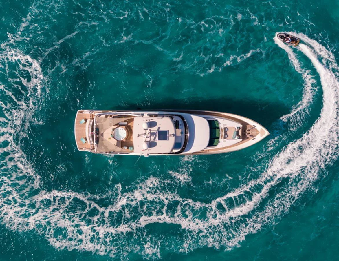 A stunning aerial view of a yacht cruising through vibrant turquoise waters, accompanied by a jet ski. aboard MR & MRS SMITH Yacht for Sale