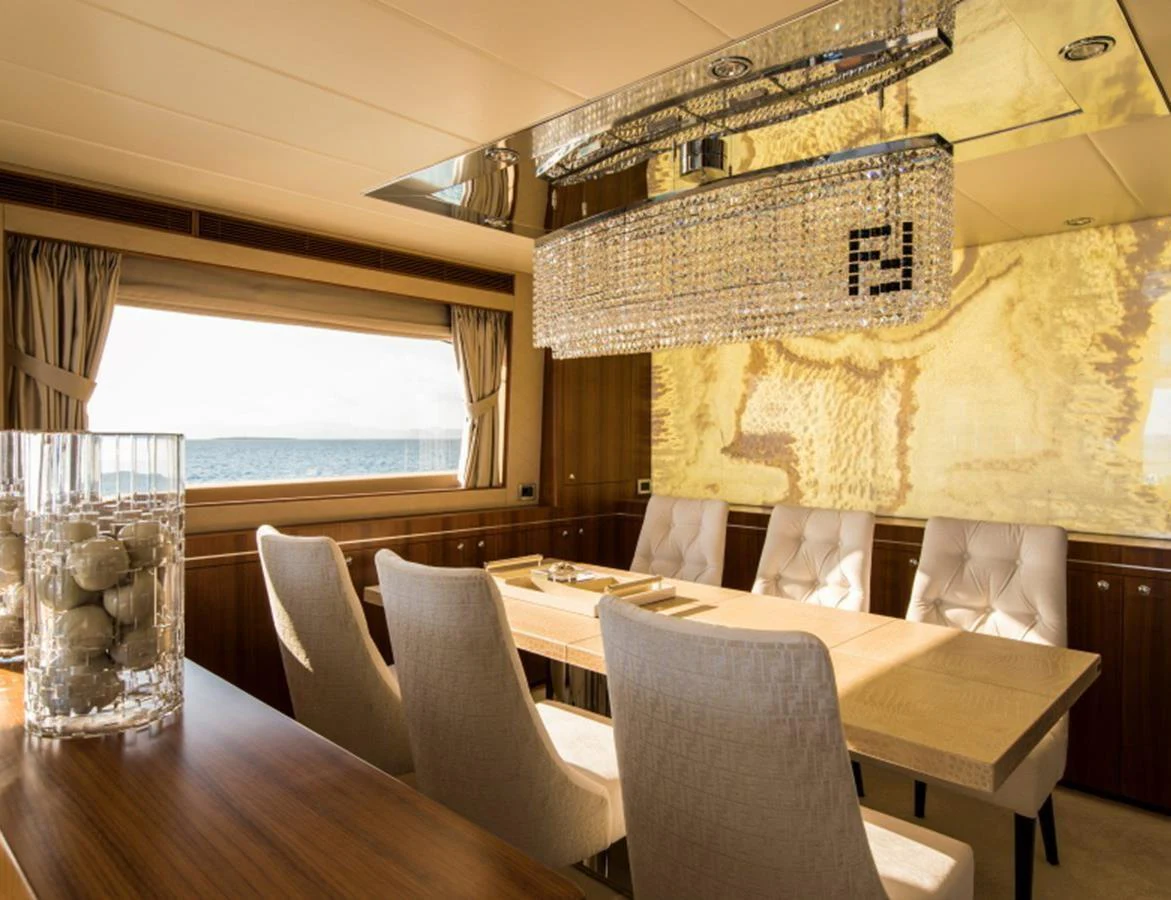 The yacht's dining area features elegant seating and a stunning chandelier, with a large window offering a beautiful sea view. aboard MR & MRS SMITH Yacht for Sale