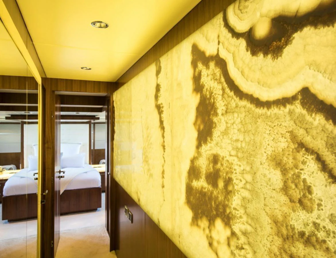 A luxurious hallway with a striking backlit onyx wall leading to a well-appointed stateroom. aboard MR & MRS SMITH Yacht for Sale