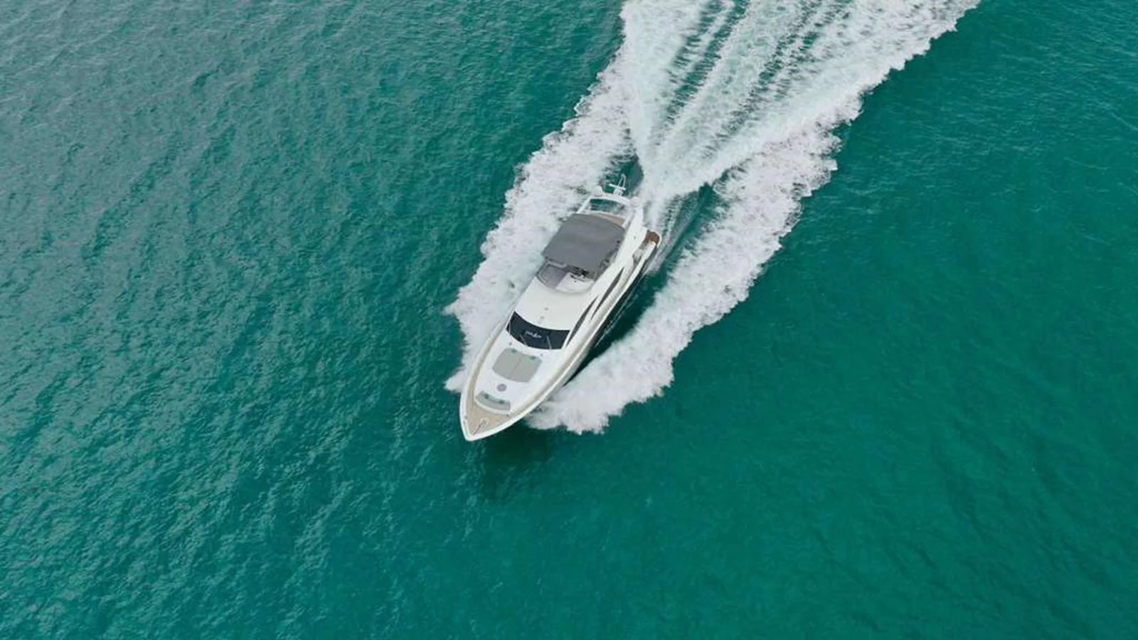 A sleek yacht cruises through clear turquoise waters, leaving a trail of white wake behind. aboard 2006 SUNSEEKER MANHATTAN 'FINS UP' Yacht for Sale