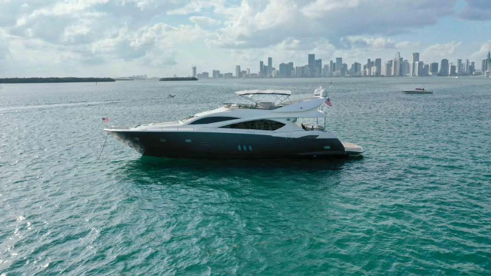 A sleek yacht cruises on calm waters with a city skyline in the background. aboard 2006 SUNSEEKER MANHATTAN 'FINS UP' Yacht for Sale