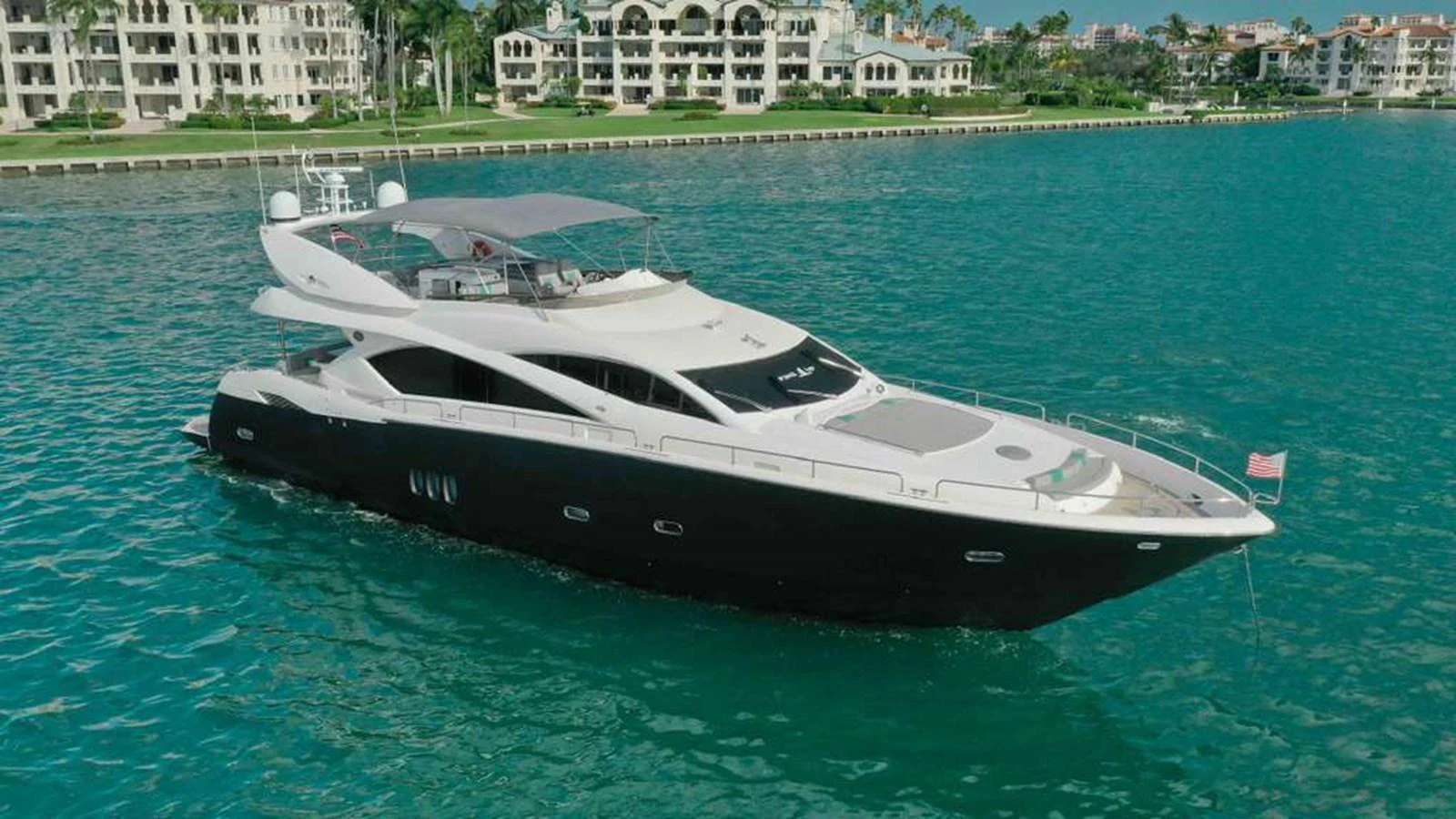 A sleek and modern yacht cruising near a luxurious waterfront community. aboard 2006 SUNSEEKER MANHATTAN 'FINS UP' Yacht for Sale