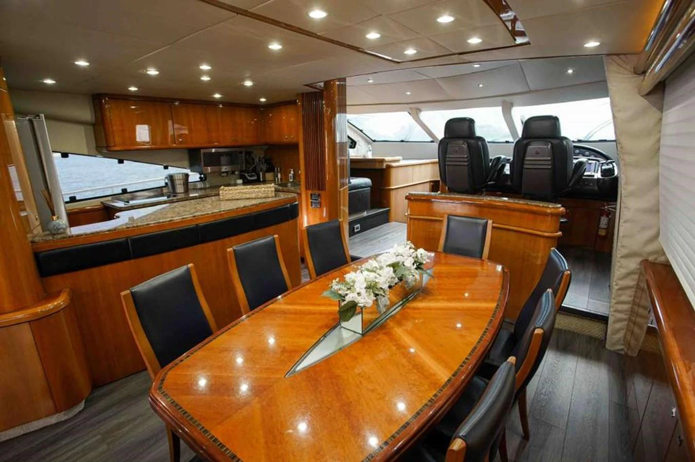 The yacht's dining area features a polished wooden table and comfortable seating, with a view of the helm station. aboard 2006 SUNSEEKER MANHATTAN 'FINS UP' Yacht for Sale