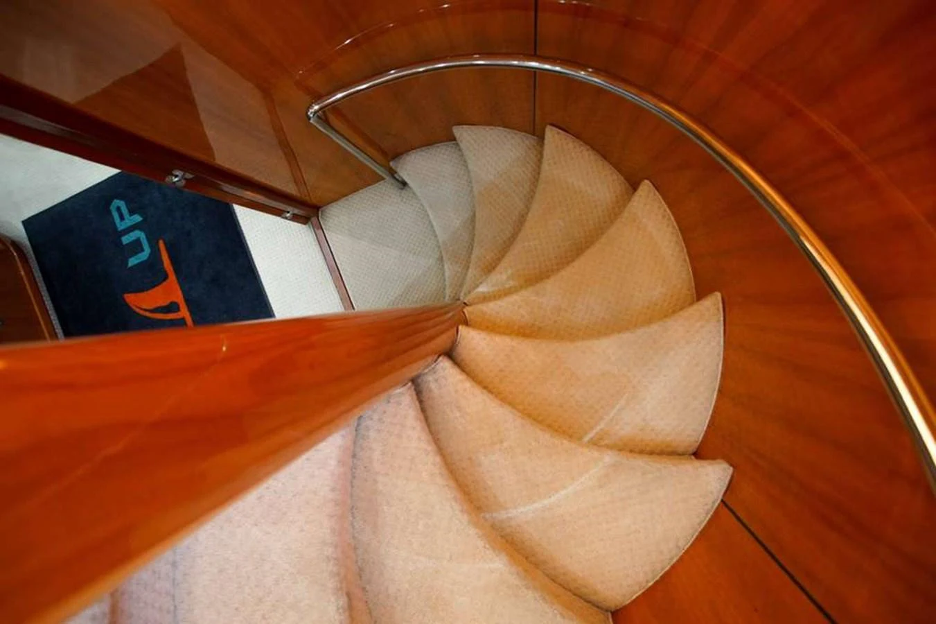 A beautifully crafted spiral staircase with wooden paneling and plush carpeting. aboard 2006 SUNSEEKER MANHATTAN 'FINS UP' Yacht for Sale