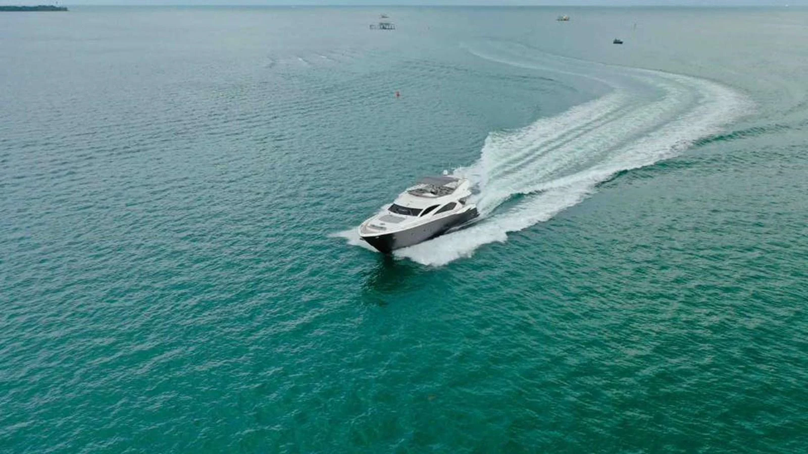 A sleek yacht cruises swiftly over calm, turquoise waters, leaving a trail of white wake behind. aboard 2006 SUNSEEKER MANHATTAN 'FINS UP' Yacht for Sale