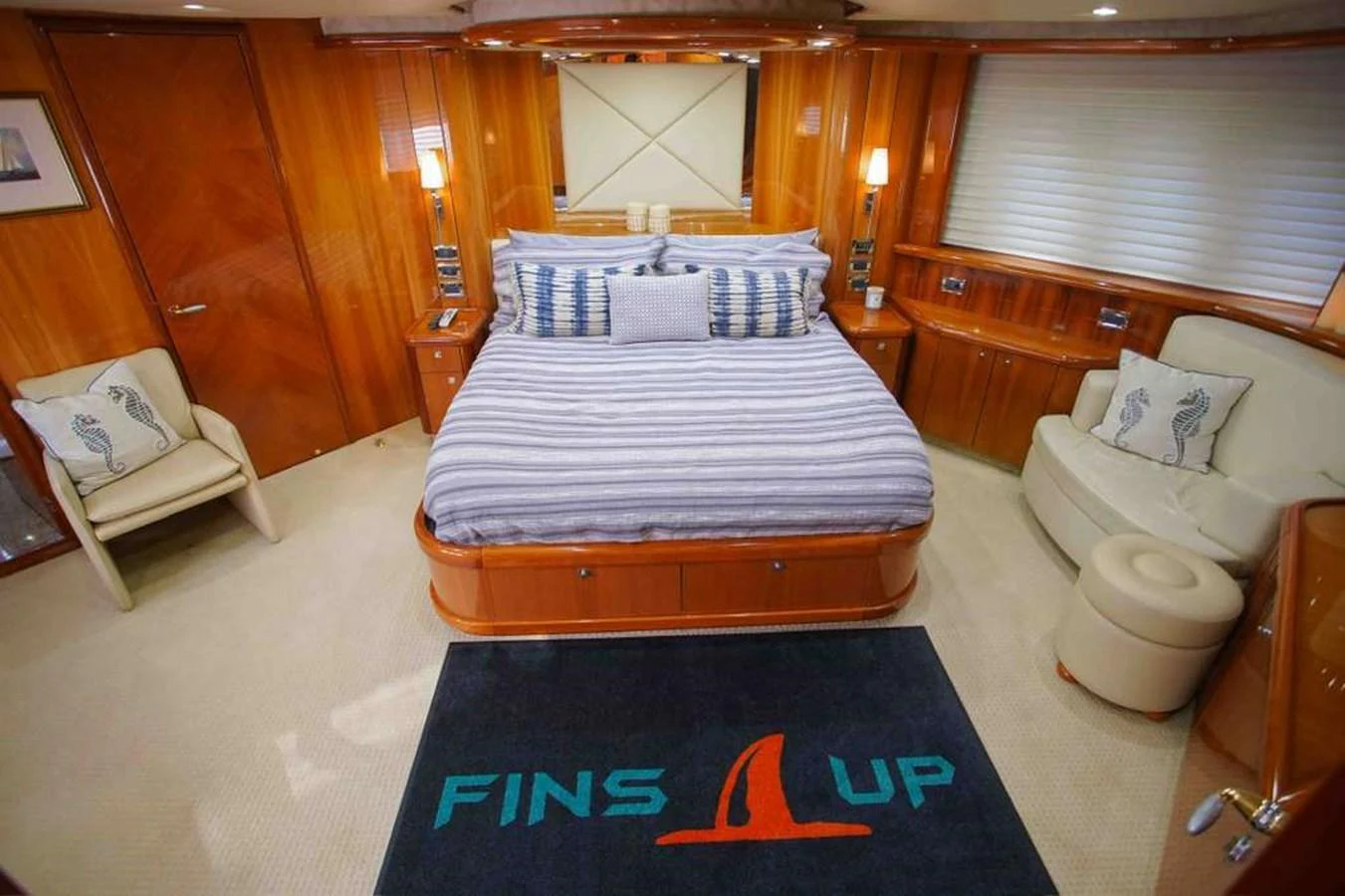 The master stateroom features a luxurious bed with striped bedding and warm wooden accents. aboard 2006 SUNSEEKER MANHATTAN 'FINS UP' Yacht for Sale