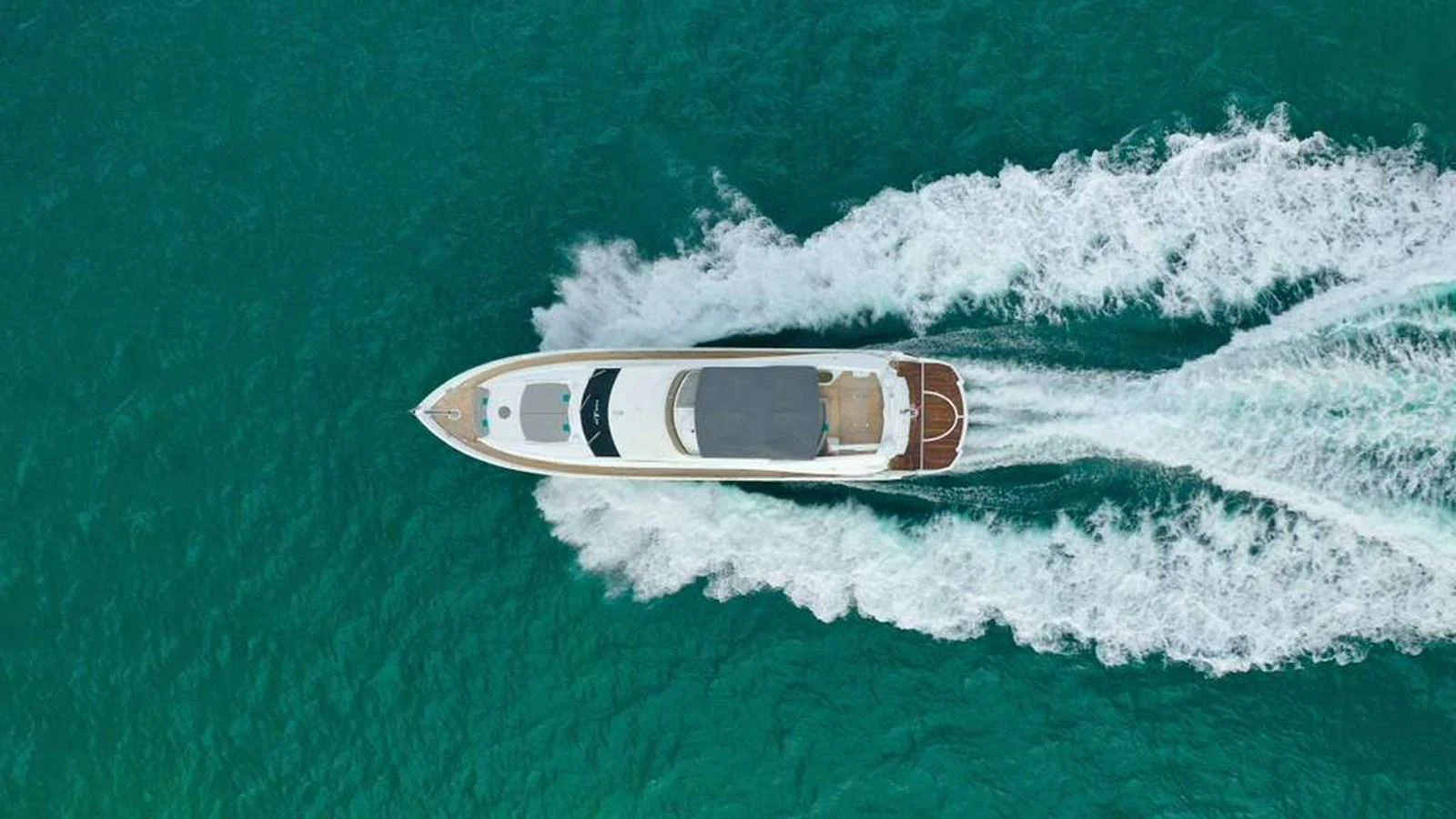 A sleek yacht cruises through clear turquoise waters, leaving a trail of white wake behind. aboard 2006 SUNSEEKER MANHATTAN 'FINS UP' Yacht for Sale
