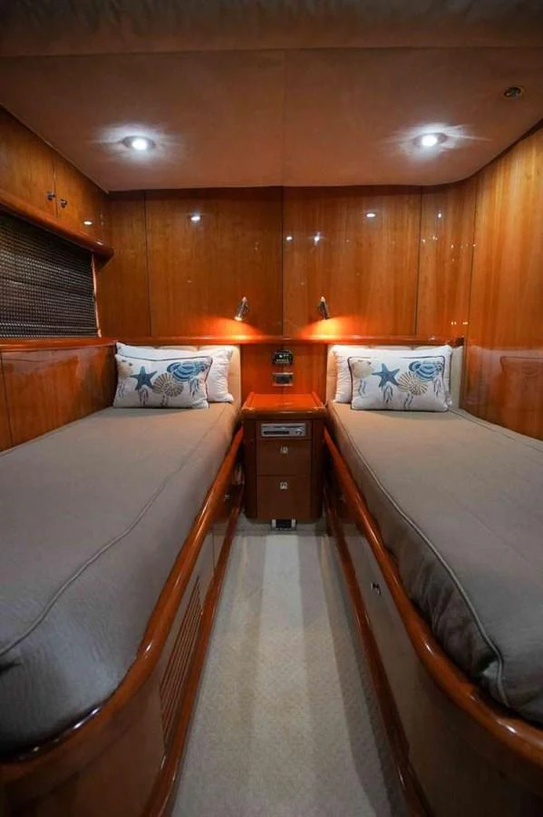 The twin stateroom features two single beds with plush bedding and warm wooden paneling. aboard 2006 SUNSEEKER MANHATTAN 'FINS UP' Yacht for Sale