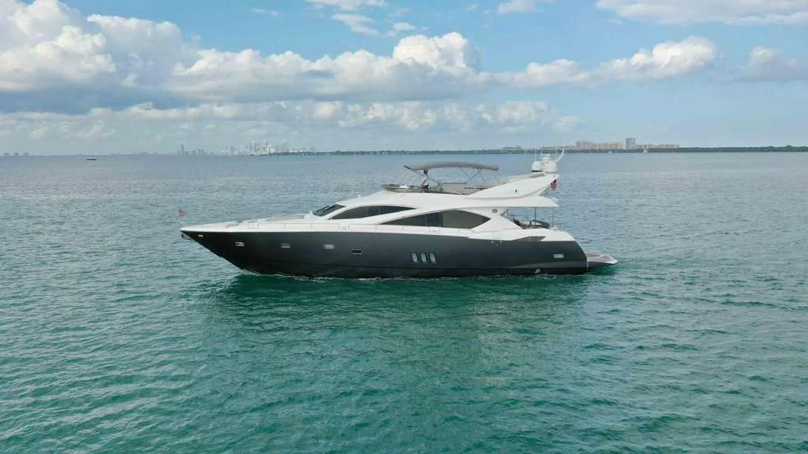 A sleek and modern yacht cruises gracefully on calm waters under a partly cloudy sky. aboard 2006 SUNSEEKER MANHATTAN 'FINS UP' Yacht for Sale