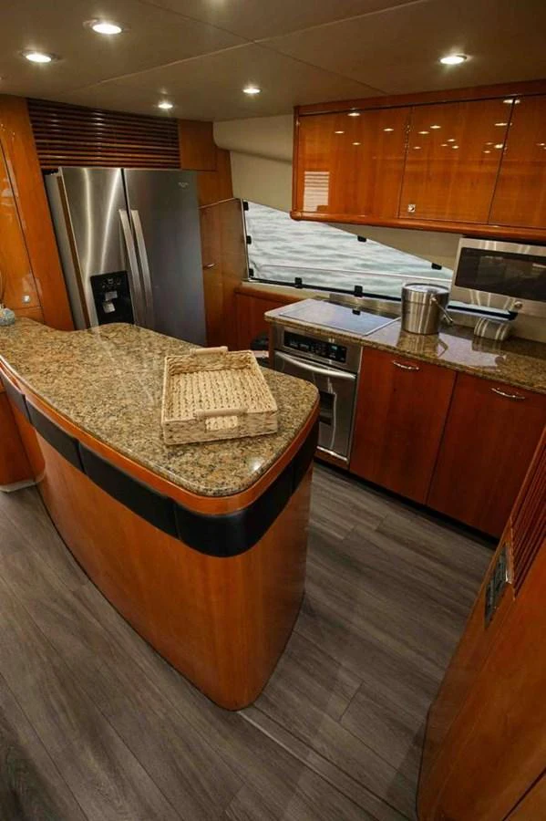 The yacht's galley features modern appliances and elegant wood cabinetry, creating a warm and functional space. aboard 2006 SUNSEEKER MANHATTAN 'FINS UP' Yacht for Sale