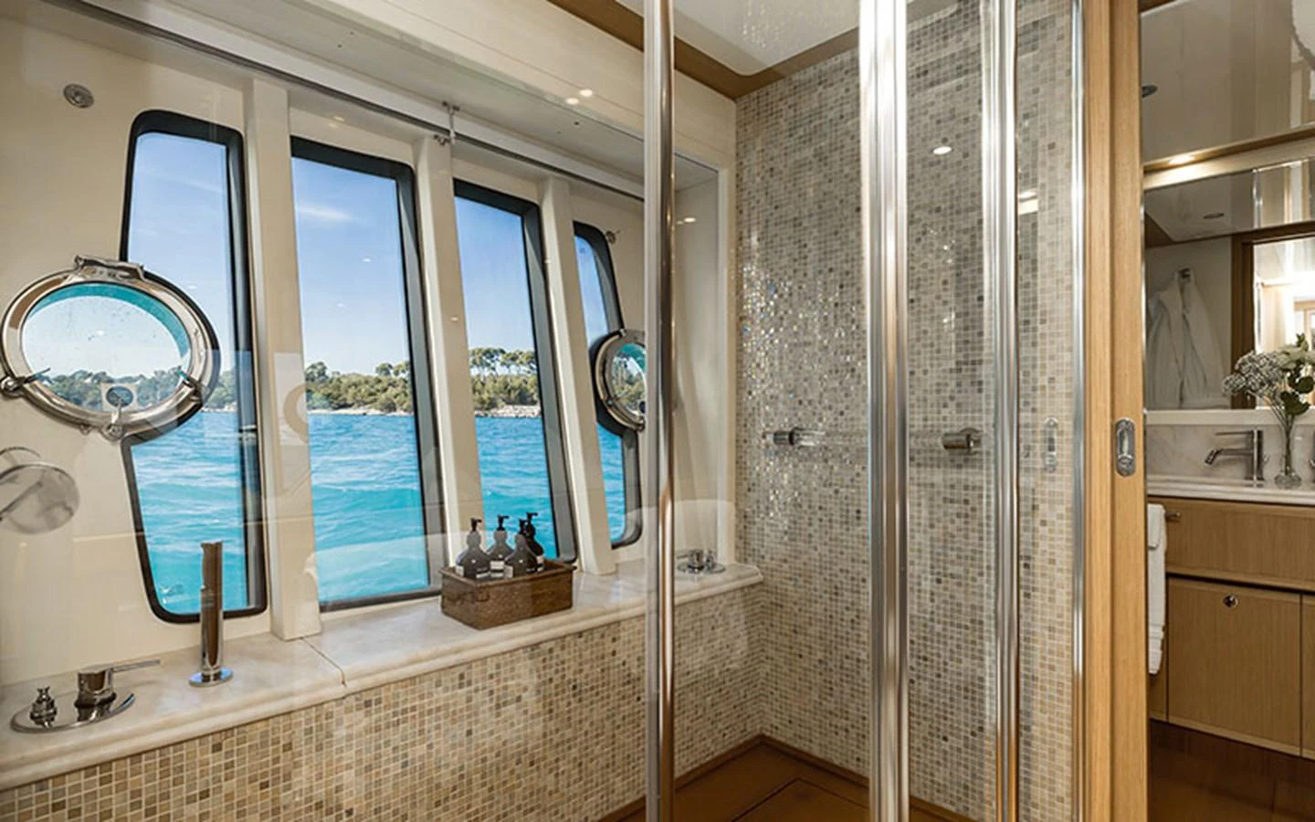 The yacht's bathroom features a large window with a stunning view of the sea, complemented by elegant mosaic tiles and modern fixtures. aboard ONYX Yacht for Sale