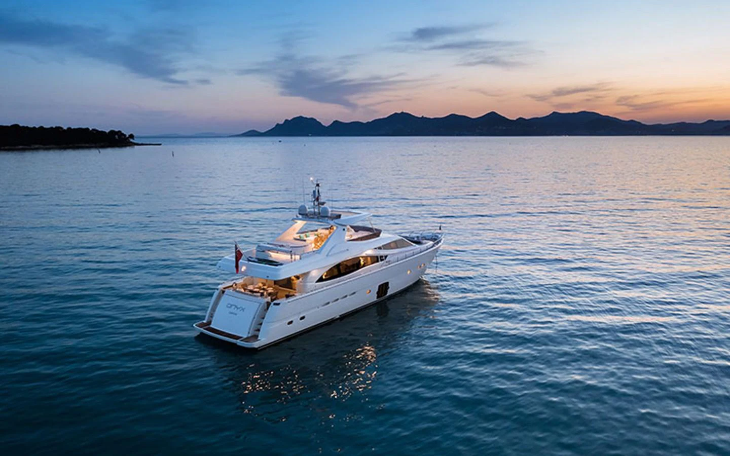 A luxurious yacht glides peacefully on calm waters at sunset, showcasing its elegant design and serene surroundings. aboard ONYX Yacht for Sale