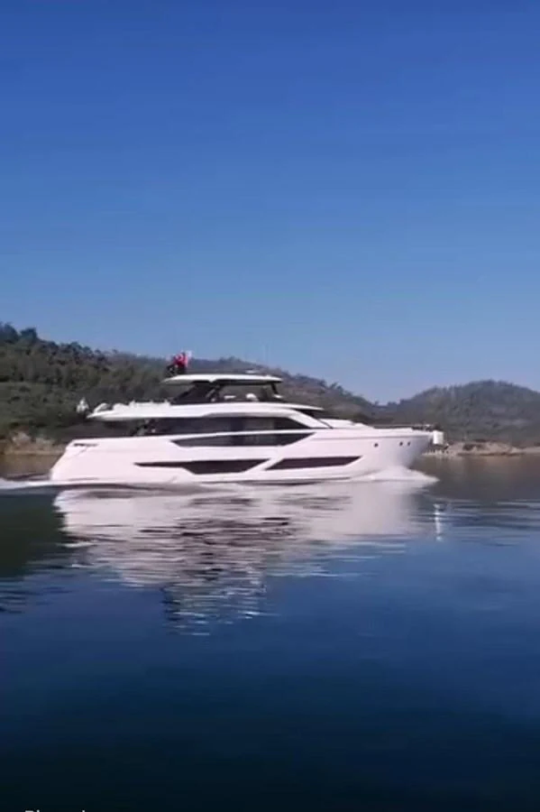 A sleek, modern yacht glides smoothly on calm waters with a scenic backdrop. aboard TBN 860 Yacht for Sale