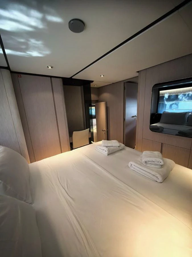 A cozy stateroom featuring a neatly made bed with folded towels and soft lighting. aboard TBN 860 Yacht for Sale