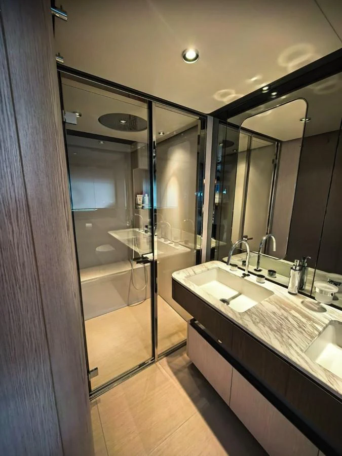 The yacht's bathroom features a sleek design with a glass-enclosed shower and a double sink vanity. aboard TBN 860 Yacht for Sale