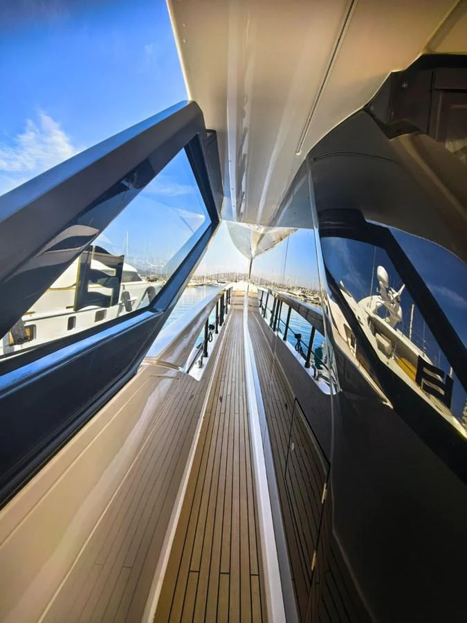 A sleek side deck with polished wood flooring and reflective windows, leading towards the bow. aboard TBN 860 Yacht for Sale