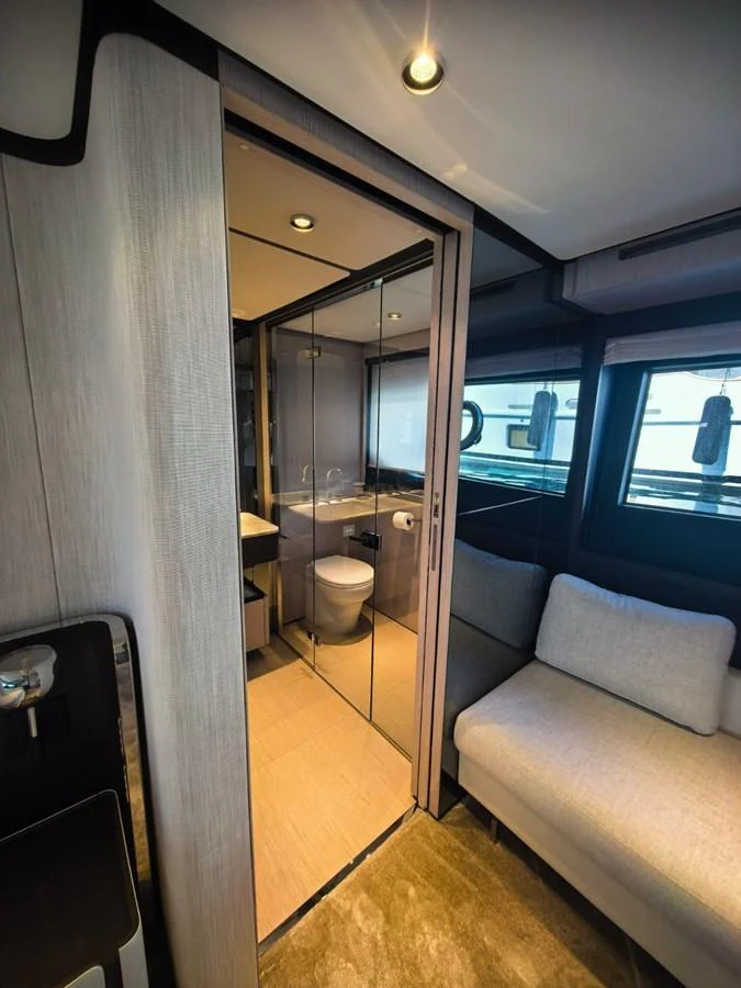 A modern yacht bathroom with a glass-enclosed shower and adjacent seating area. aboard TBN 860 Yacht for Sale