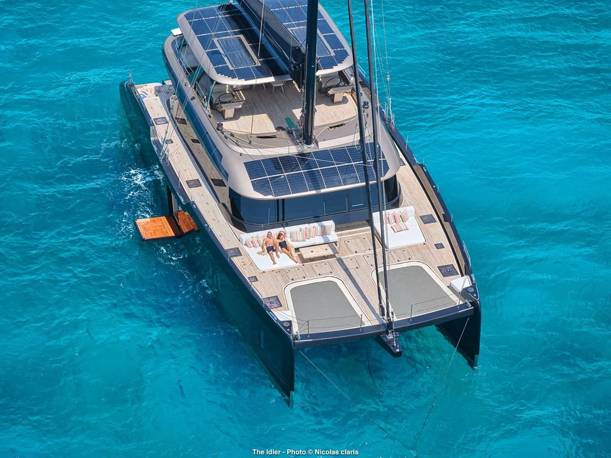 A luxurious catamaran with spacious aft deck and solar panels glides through crystal-clear waters. aboard THE IDLER Yacht for Sale
