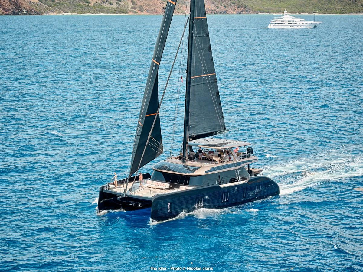 A sleek and modern catamaran sails gracefully on clear blue waters. aboard THE IDLER Yacht for Sale