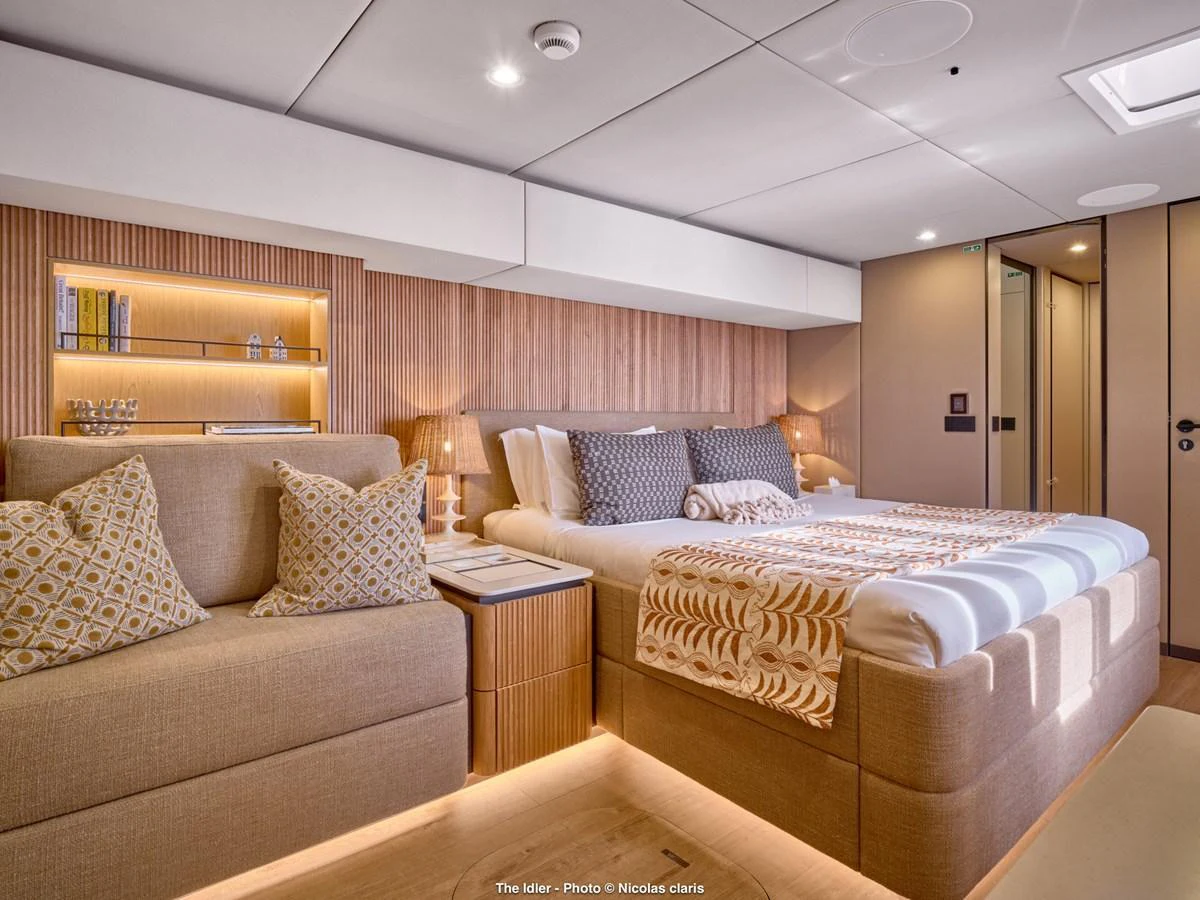 The master stateroom features a luxurious bed, cozy seating area, and elegant lighting. aboard THE IDLER Yacht for Sale