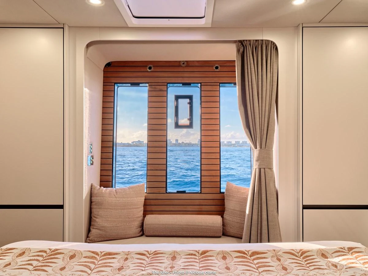This cozy stateroom features a large window with a stunning ocean view, complemented by elegant decor and comfortable seating. aboard THE IDLER Yacht for Sale
