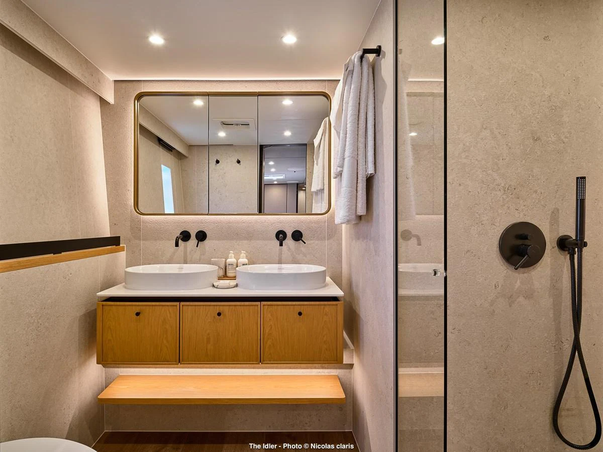 The yacht's bathroom features a modern design with dual sinks and a spacious shower area. aboard THE IDLER Yacht for Sale