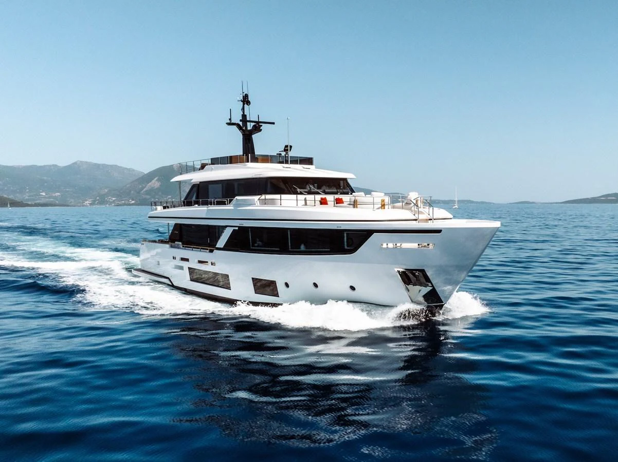 A sleek and modern yacht cruising on calm blue waters with a picturesque coastline in the background. aboard AT ONE Yacht for Sale